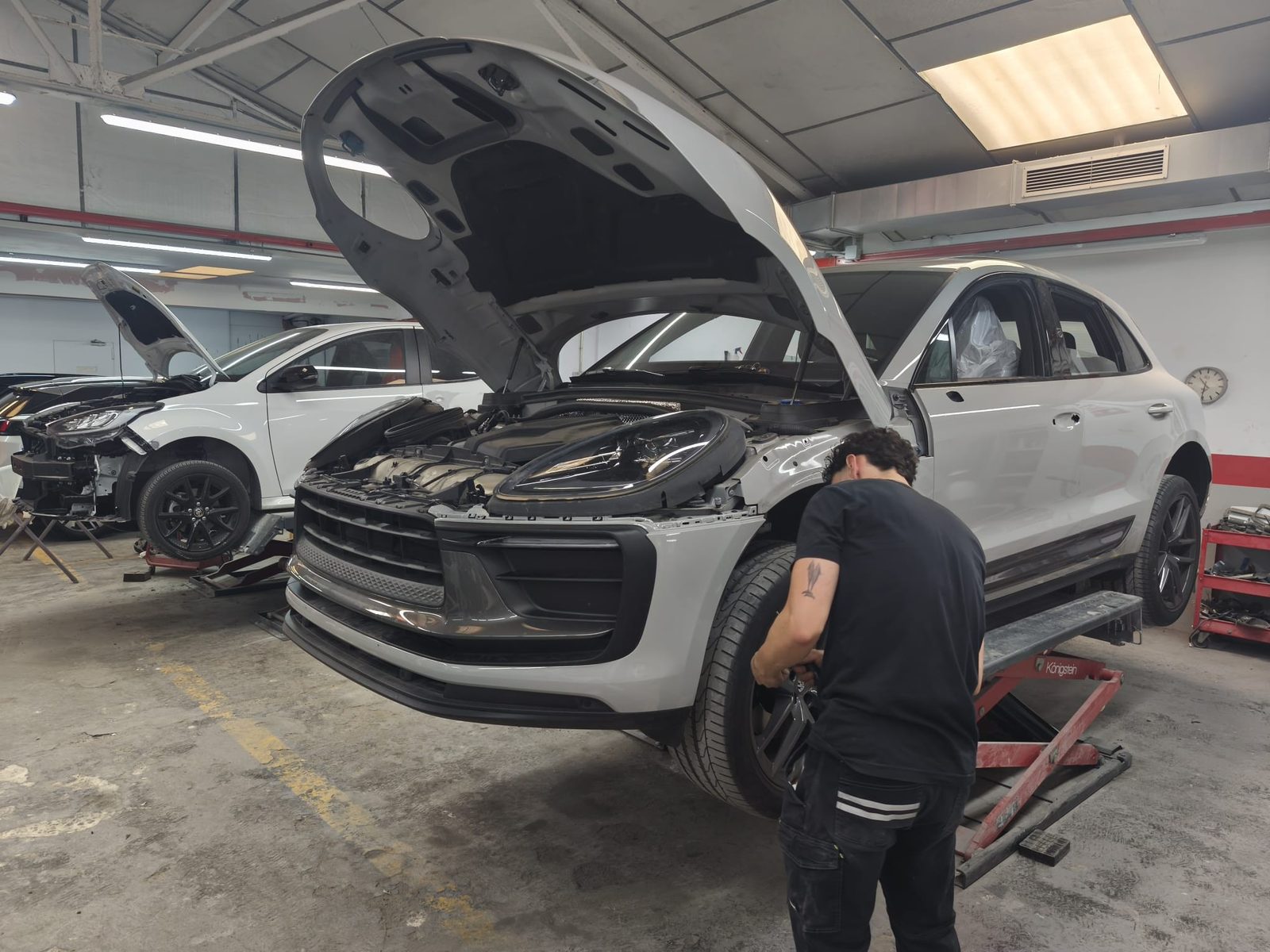 Tècnic del taller treballant a la roda d’un SUV blanc elevat al pont